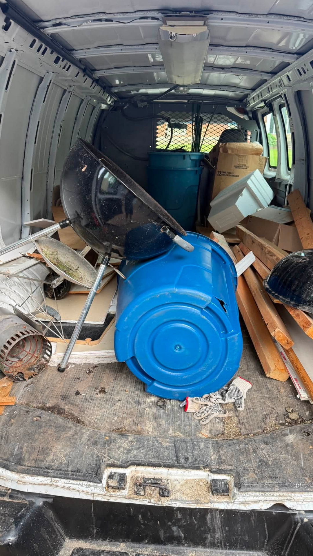 Van loaded with a grill, barrels, and yard cleanup items