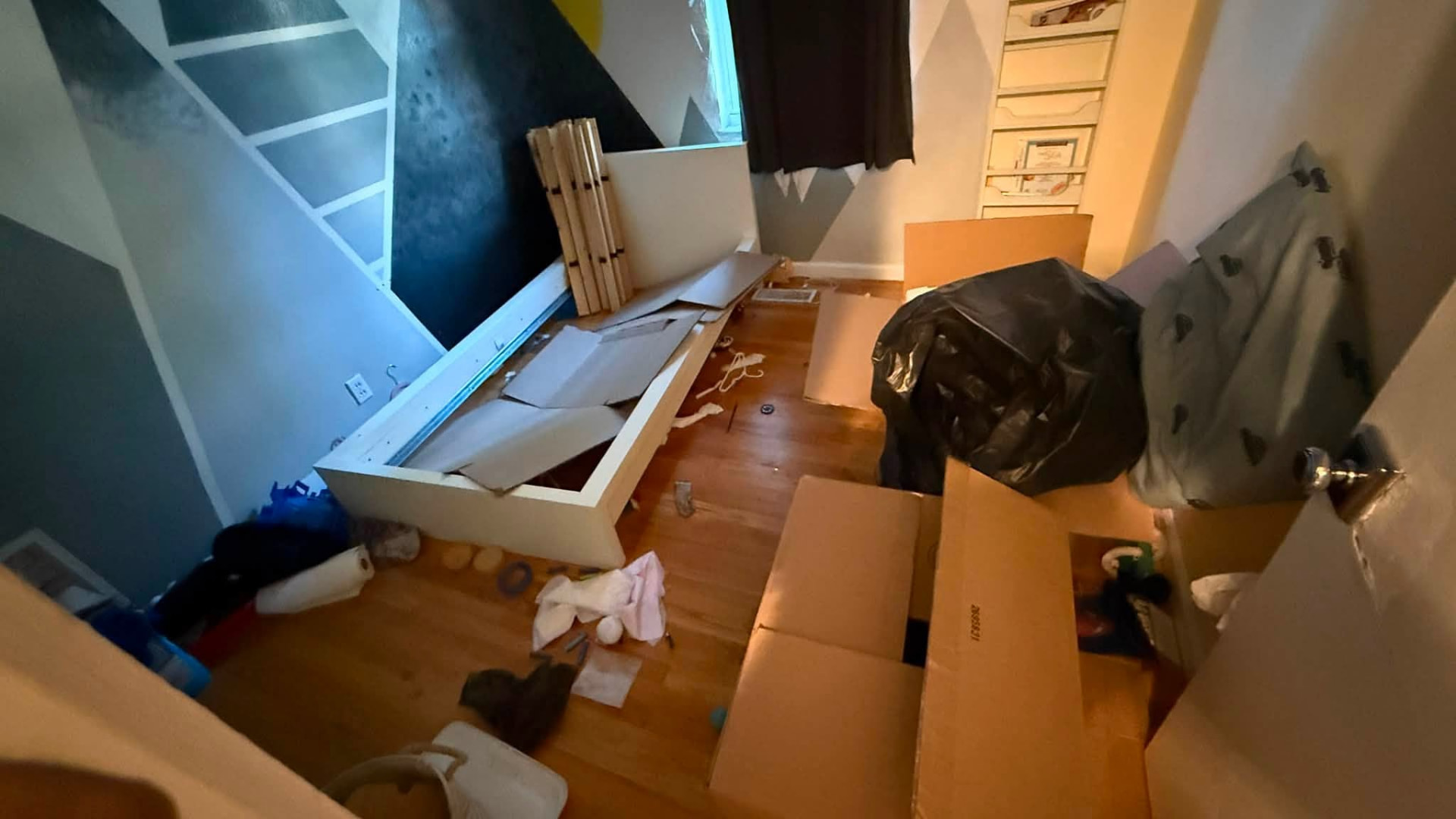 Bedroom with a disassembled bed frame and boxes during a cleanout